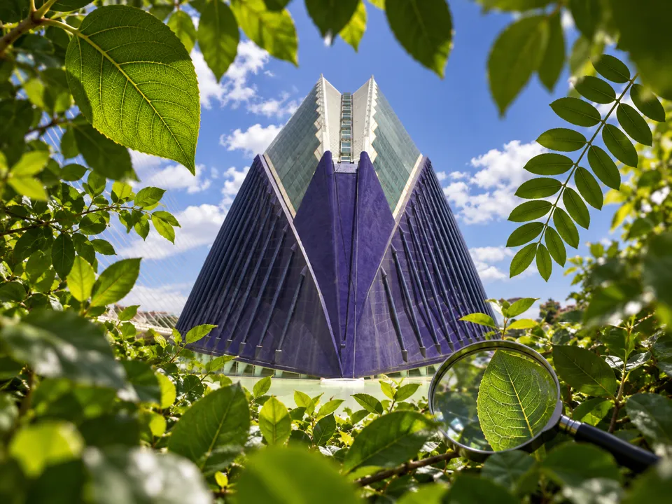 AI-generated illustration: CaixaForum València exterior framed by ordered and irregular leaf patterns with a small magnifying glass.