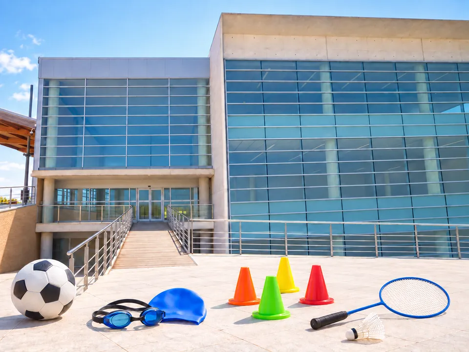 AI-generated illustration: empty Centro Deportivo Parc Central exterior with football, swimming and multisport equipment.